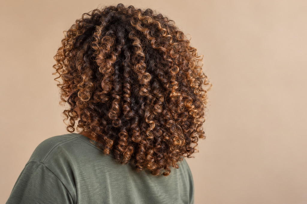 She has curly, caramel highlighted hair with springy, defined spiral ringlets about the width of a marker pen, with plenty of volume.